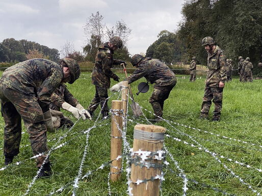Bau eines Flandernzaunes mit Holzpfählen und Bandstacheldraht.