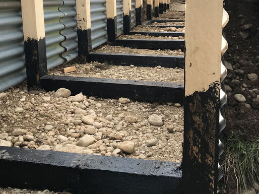 Versiegelung der Holzrahmen mit Teer, bevor diese ins Grabensystem eingelassen werden.